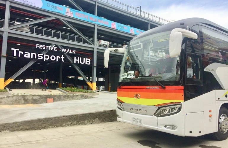 A bus pulling out of the Festive Walk Transport Hub in Iloilo City, under the hub's lit sign
